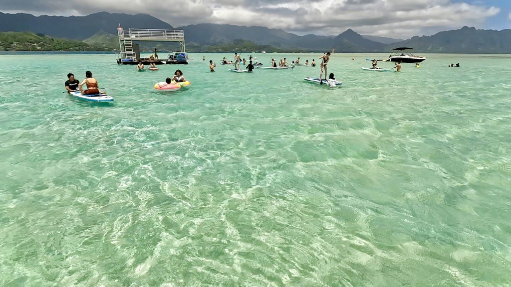 カネオヘ湾サンドバーで遊具を楽しむ参加者たち。ポンツーン上で思い思いに遊ぶ様子