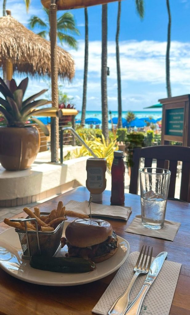 デュークス・ワイキキのマンゴーバーベキューベーコンバーガー。海を背景に映える一枚。