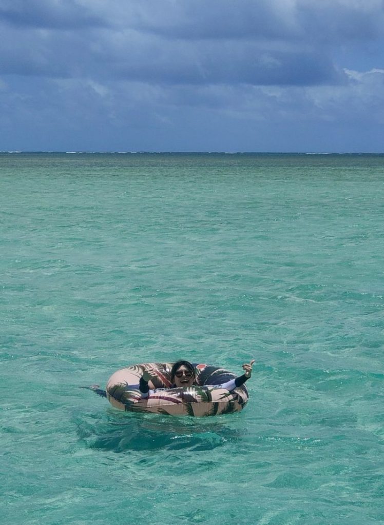 カネオヘ湾サンドバーで浮き輪を使って海に浮かぶ筆者。透き通る海と青空が広がる絶景