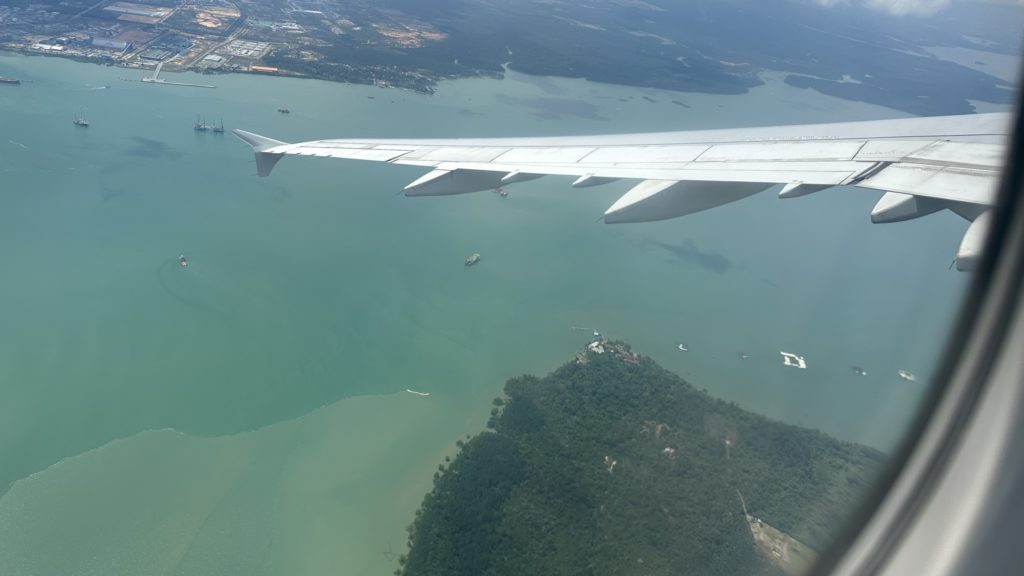 飛行機の窓から見える翼と青い海の景色。快適なフライトをイメージさせる写真